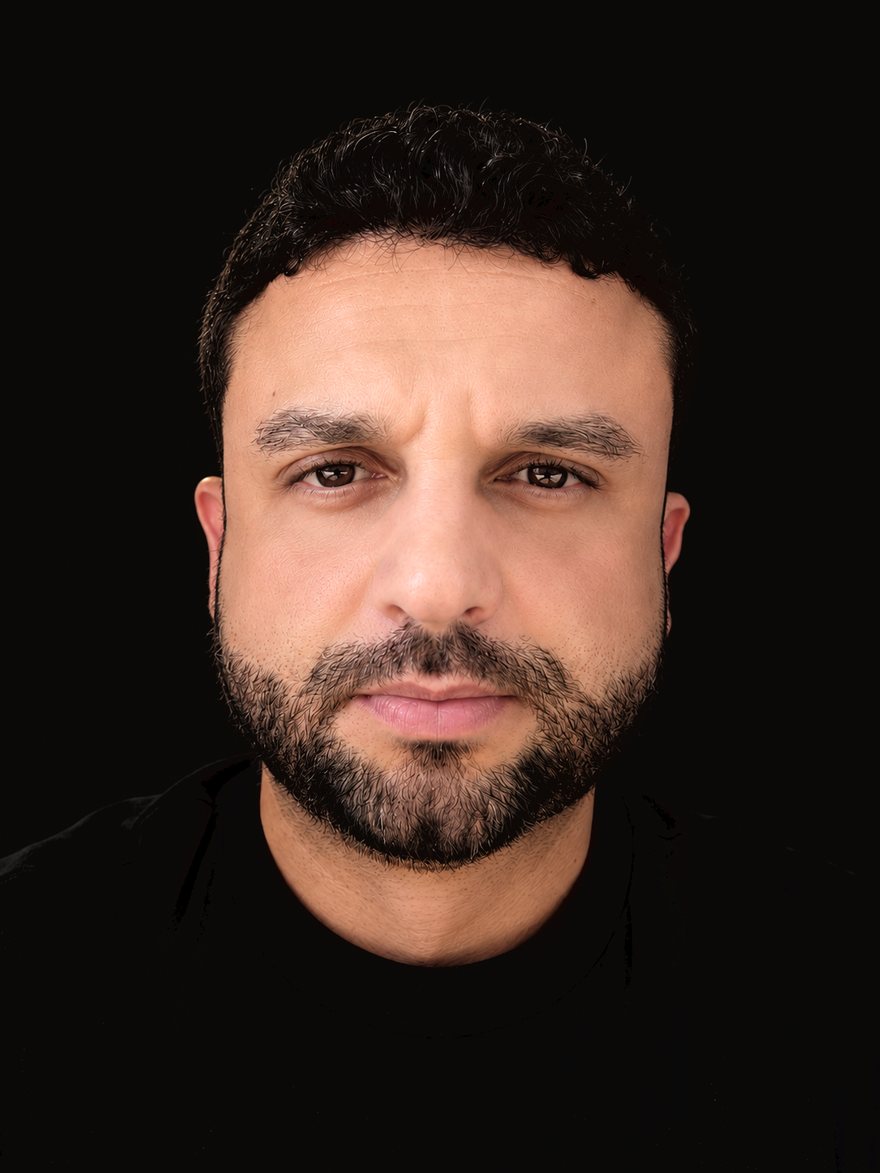 Retrato de Bruno Moradillo, de camiseta preta, sobre fundo escuro.